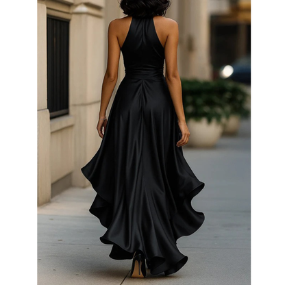 Back view of the black satin halter dress worn by a model walking away, showing open shoulders and the ruffled high-low hem. 12