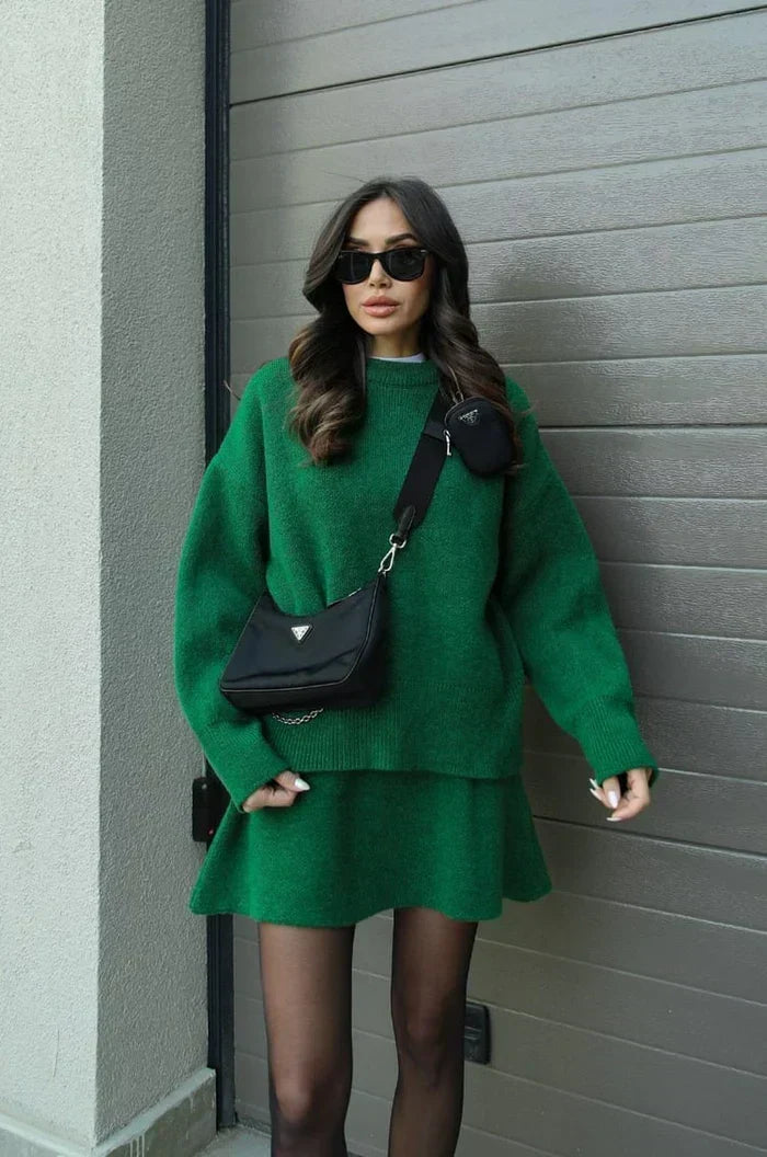 Model in the green set with a black crossbody bag, standing against a garage door 8
