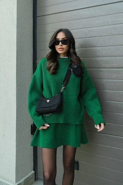 Model in the green set with a black crossbody bag, standing against a garage door 8