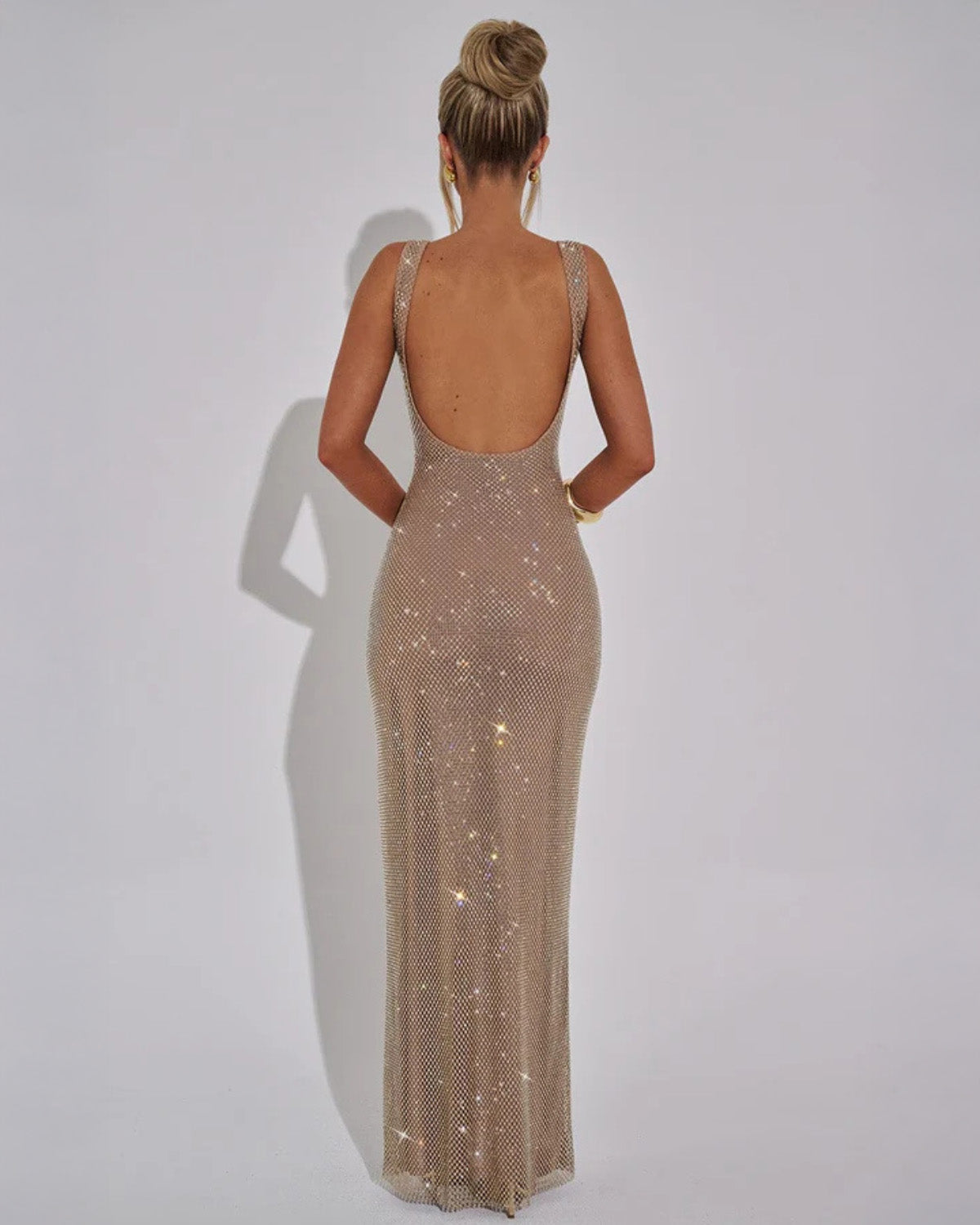 Back view of the gold-beige sparkling mesh dress on a model, showing the deep open back and floor-skimming length. 4
