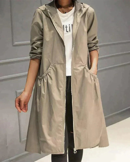 Model wearing the open-fronted, zip-up hooded raincoat in light khaki, hand in a gathered side pocket 1