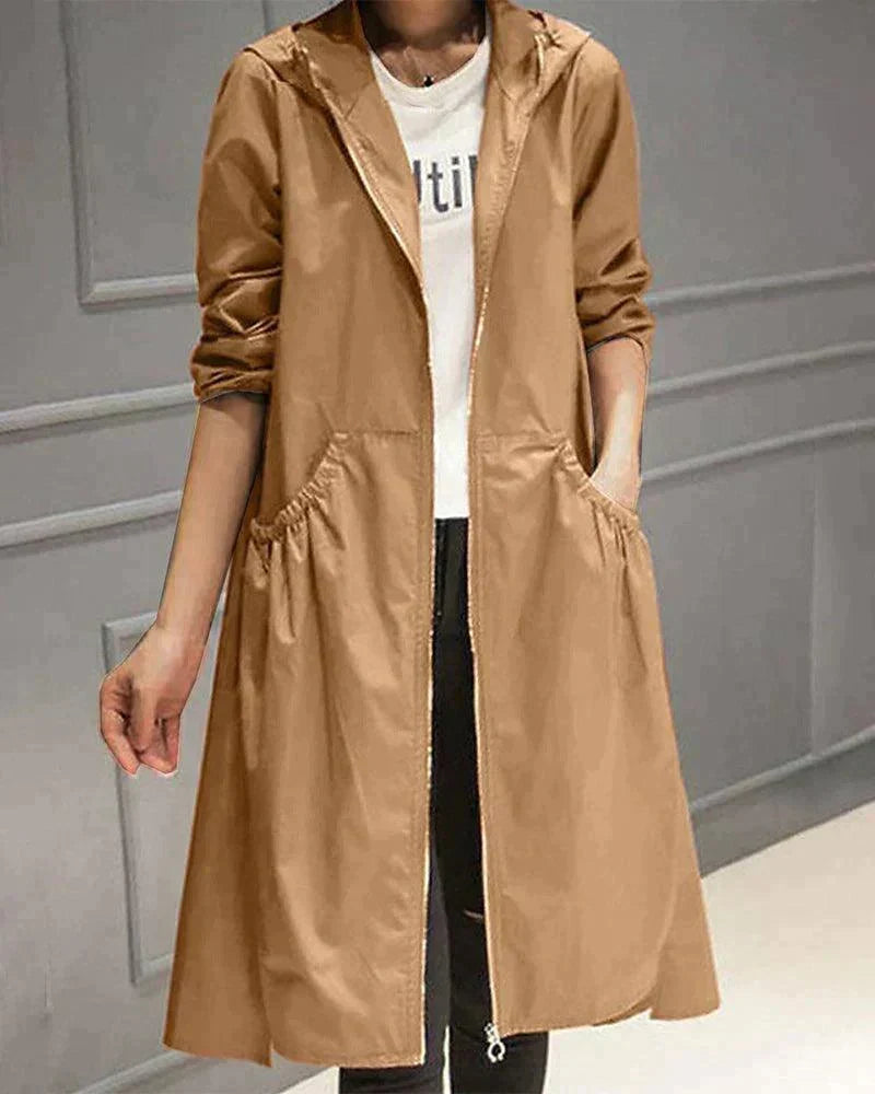 Hooded raincoat in camel tan worn unzipped over a white top, with gathered pockets visible 3