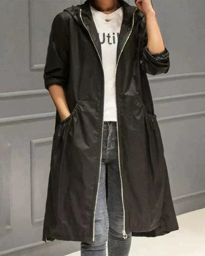 Black hooded raincoat worn open with a hand in the pocket, paired with blue jeans 4