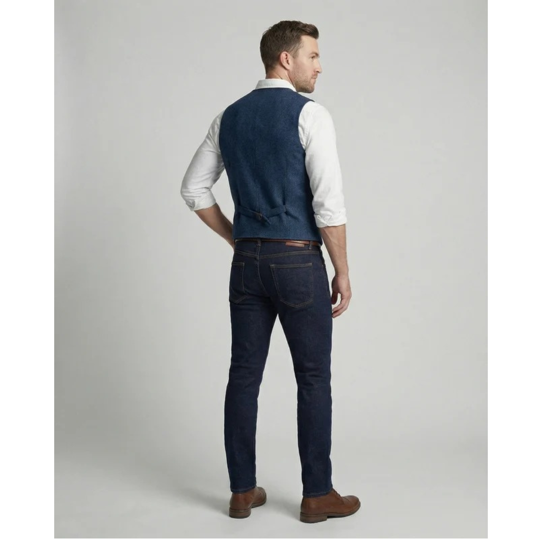 Back view of a model in the blue waistcoat showing the plain back panel and buckle strap, worn with dark jeans and boots. 4