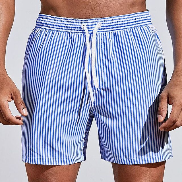 Model wearing royal blue and white vertically striped swim shorts with a white drawstring, front view with arms relaxed. 8