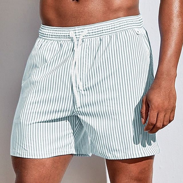Model wearing pale grey-green and white vertically striped swim shorts with a white drawstring, three-quarter front view. 10