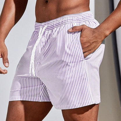 Model wearing lilac and white vertically striped swim shorts with a white drawstring, one hand tucked into the side pocket. 5