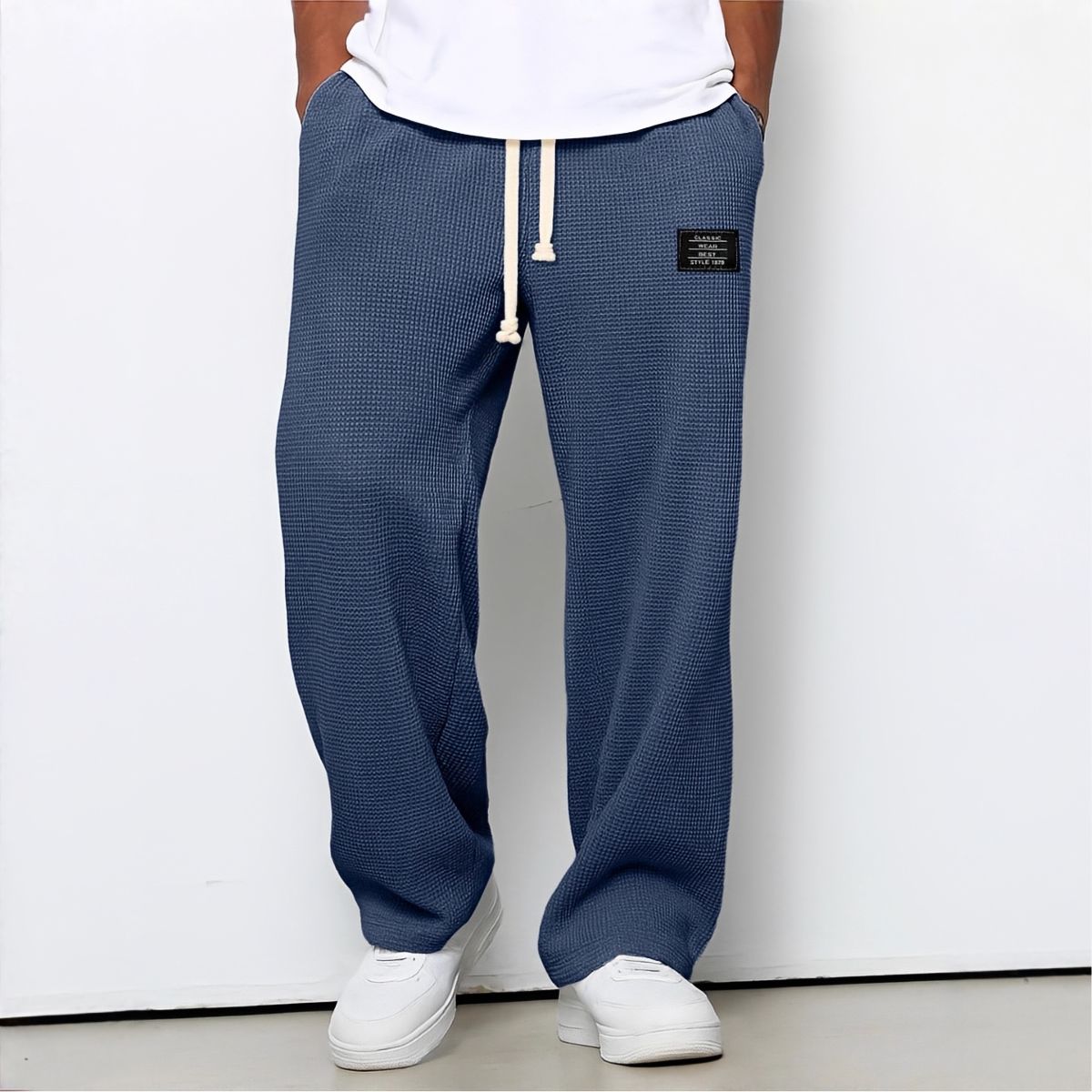 Model wearing waffle-knit wide leg trousers in navy blue with drawstring waist and white trainers 5