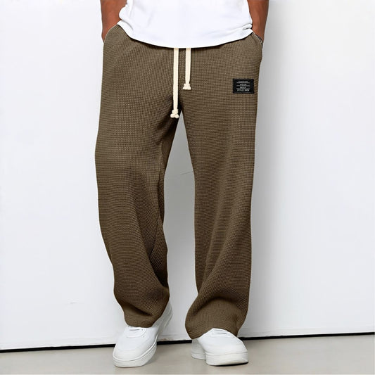 Model wearing waffle-knit wide leg trousers in brown with drawstring waist and white trainers 2