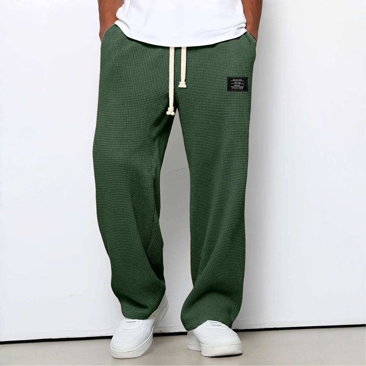 Model wearing waffle-knit wide leg trousers in dark green with drawstring waist and white trainers 4
