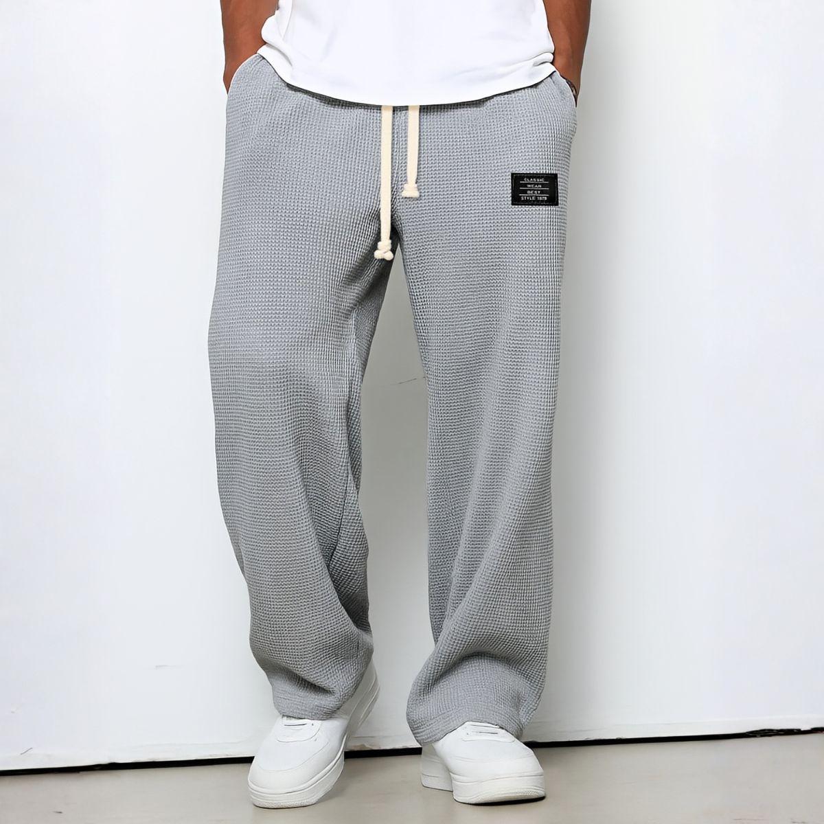Model wearing waffle-knit wide leg trousers in light grey with drawstring waist and white trainers 6