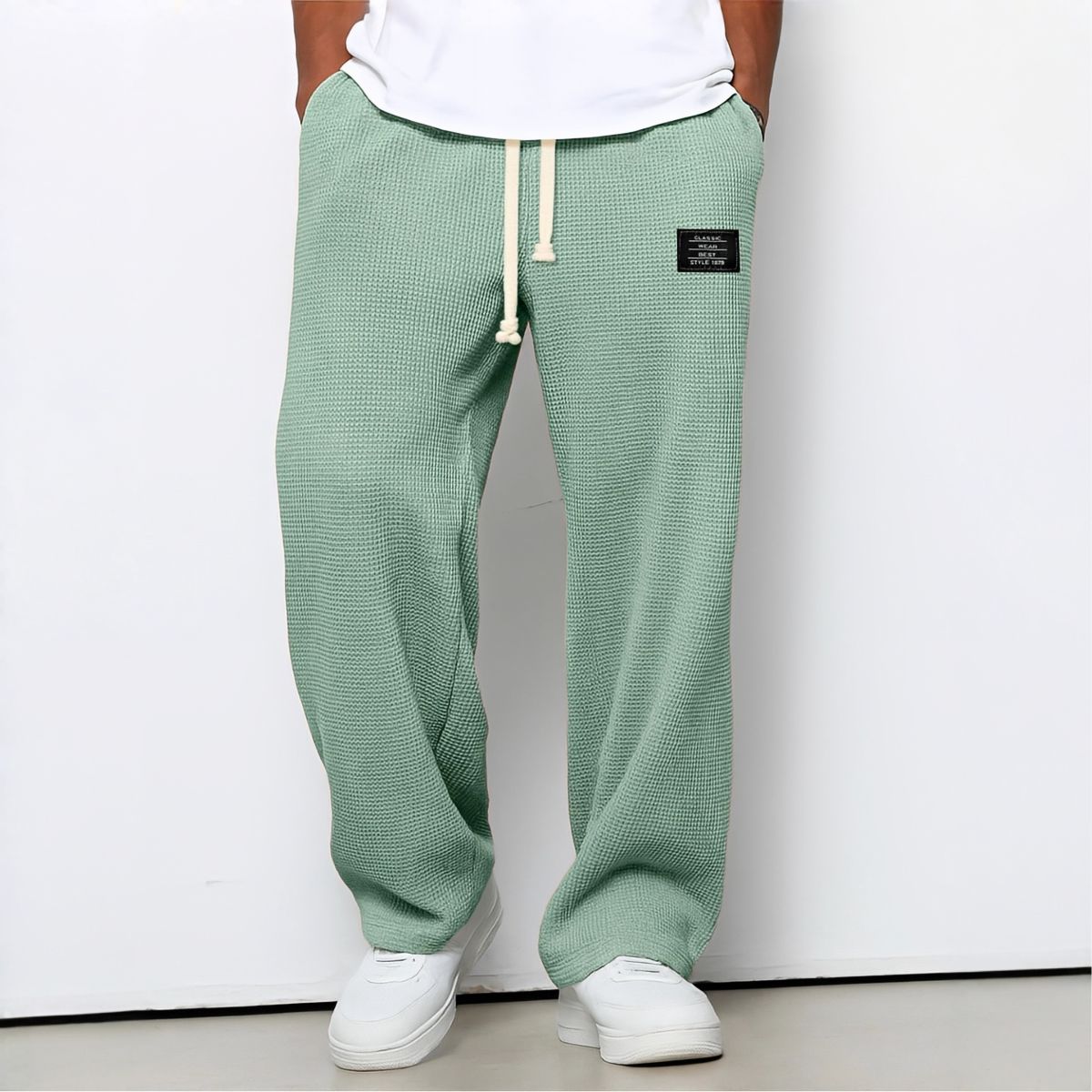 Model wearing waffle-knit wide leg trousers in mint green with drawstring waist and white trainers 9
