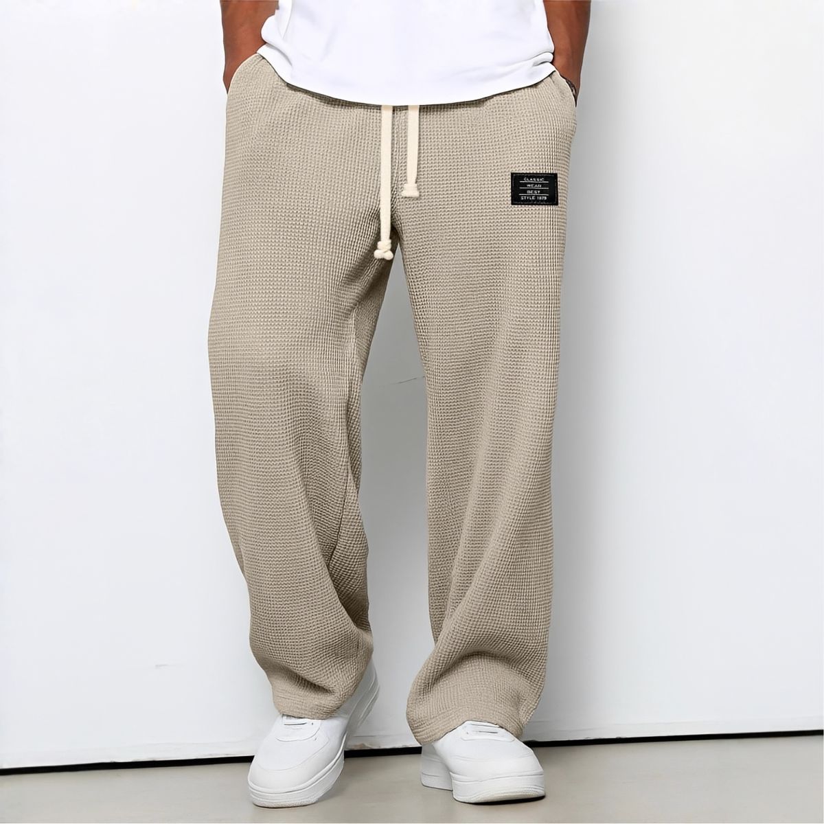 Model wearing waffle-knit wide leg trousers in beige with drawstring waist and white trainers 7