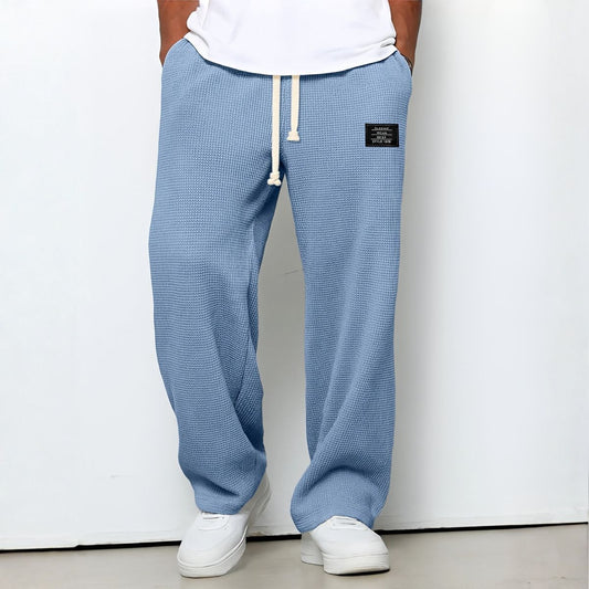 Model wearing waffle-knit wide leg trousers in light blue with drawstring waist and white trainers 1