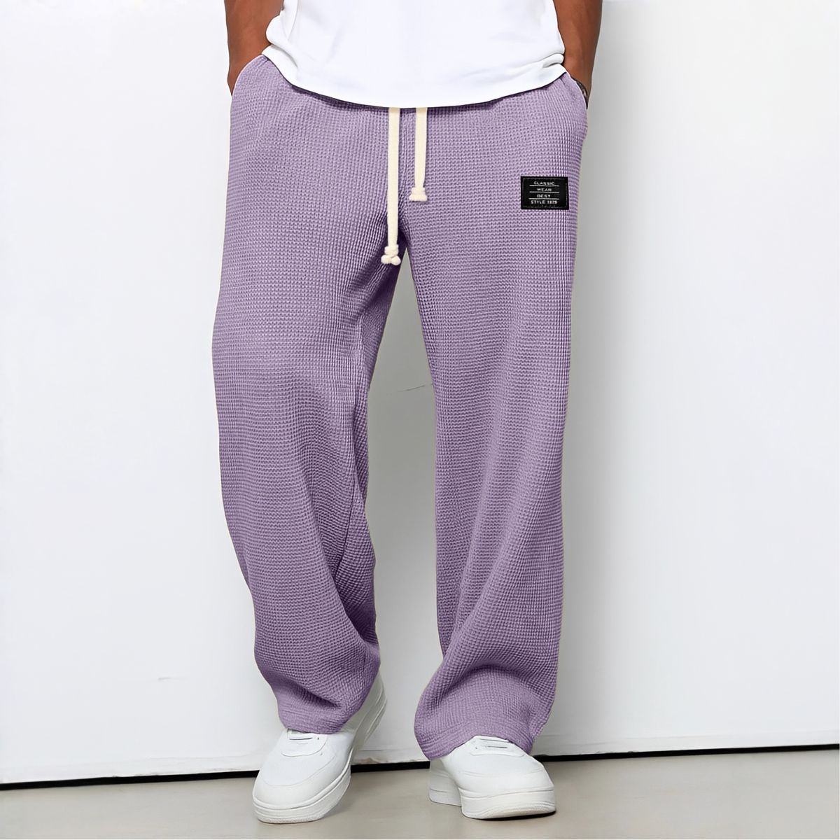 Model wearing waffle-knit wide leg trousers in lilac purple with drawstring waist and white trainers 10