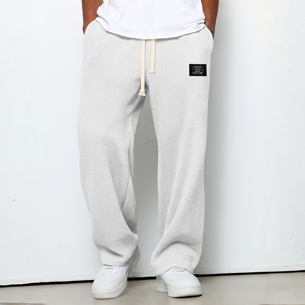 Model wearing waffle-knit wide leg trousers in off-white with drawstring waist and white trainers 8