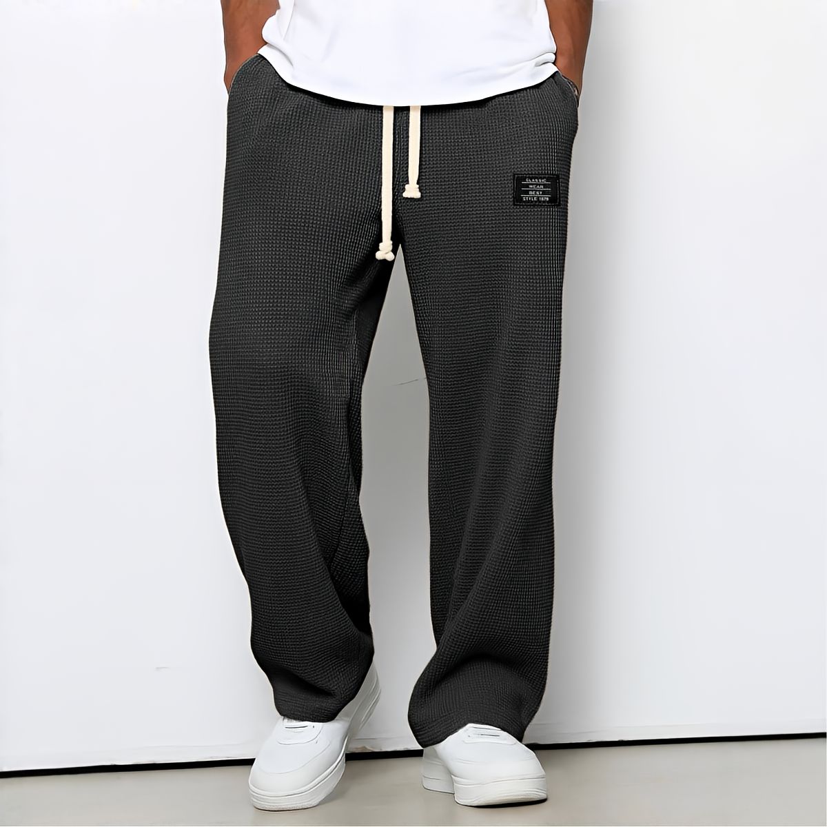 Model wearing waffle-knit wide leg trousers in charcoal grey with drawstring waist and white trainers 3