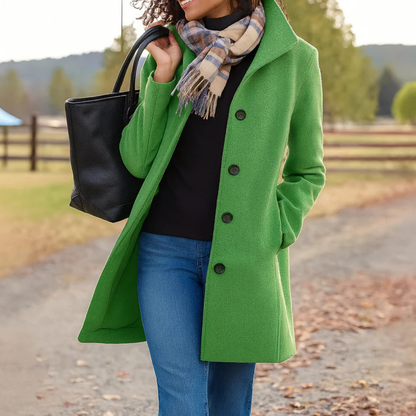 Light green version of the coat with a stand-up collar, worn with a black top, jeans, scarf and black tote. 10