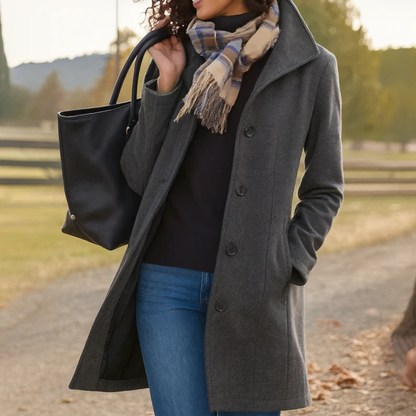 Charcoal grey version of the coat on a model, hand in pocket, styled with checked scarf and black tote on a country lane. 2