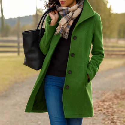 Dark green version of the coat with a high collar, worn with a black top, jeans, checked scarf and tote bag. 6