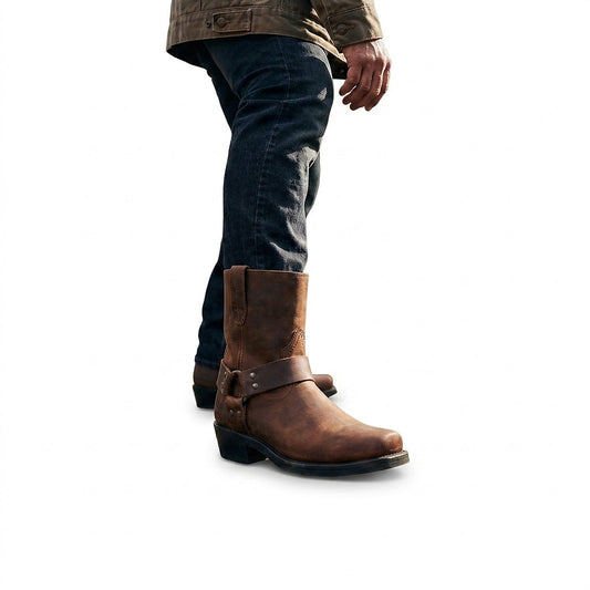 Man in dark jeans and an olive jacket walking in a brown leather harness boot with a square toe. 1