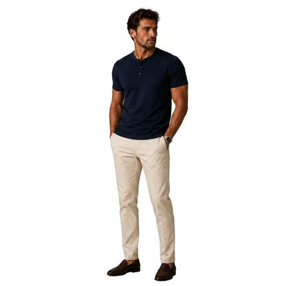 Full-length view of a man wearing the navy top with cream chinos and brown loafers, hands in pockets 2