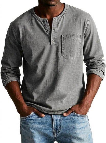 Model wearing the henley in mid grey, showing the button placket, chest pocket and pushed-up sleeves, with light blue jeans. 4