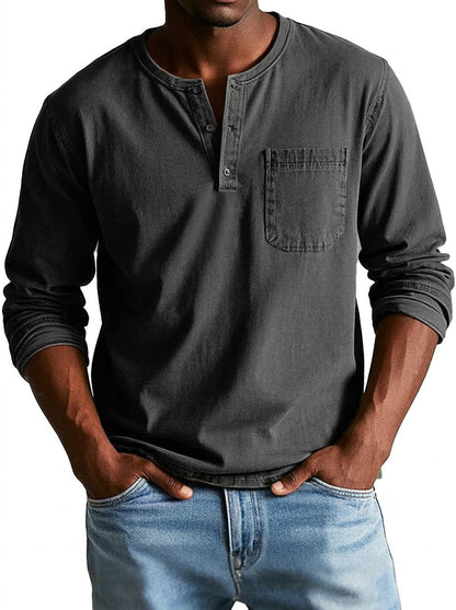 Henley in dark charcoal grey worn by a model, front view with buttoned placket and pocket, paired with light blue jeans. 5