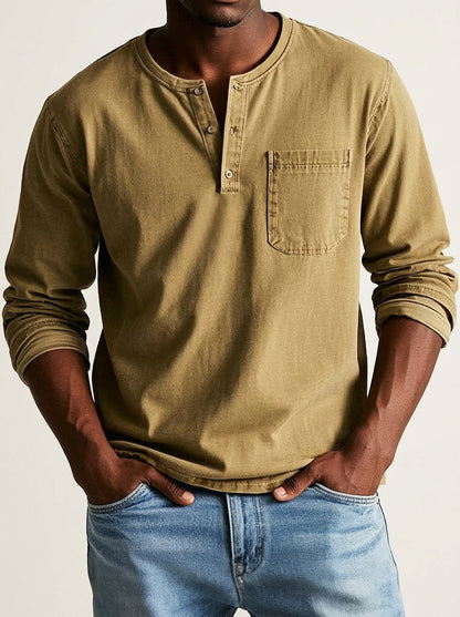 Henley in mustard khaki worn by a model, showing the three-button placket, chest pocket and rolled sleeves over light blue jeans. 7