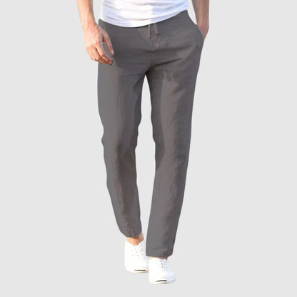 Front view of the trousers in dark grey, worn by a model with a white T-shirt and white plimsolls. 3
