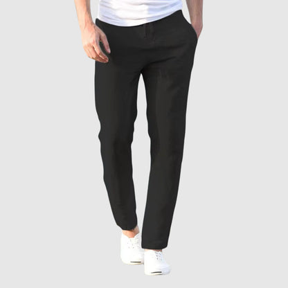 Front view of the trousers in black, worn by a model with a white T-shirt and white plimsolls. 4