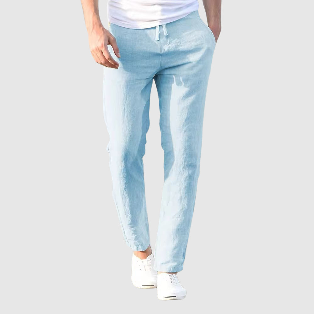 Front view of the trousers in light sky blue, with a matching drawstring, worn with a white T-shirt and white plimsolls. 5