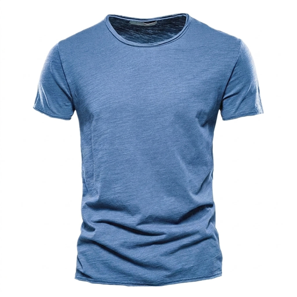 Front view of the short-sleeved crew neck t-shirt in mid blue, showing the streaky slub texture and raw-edged hems. 1