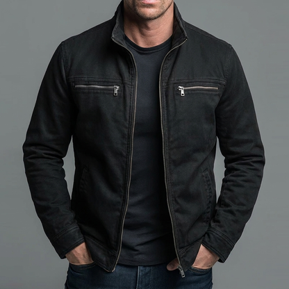 Man wearing the jacket in black with silver-toned zips, open over a black t-shirt and dark jeans, hands in pockets. 6