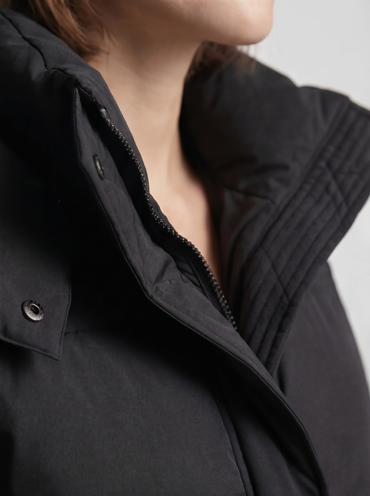 Close-up of the black jacket's collar, zip, press stud and horizontal stitching at the shoulder 7
