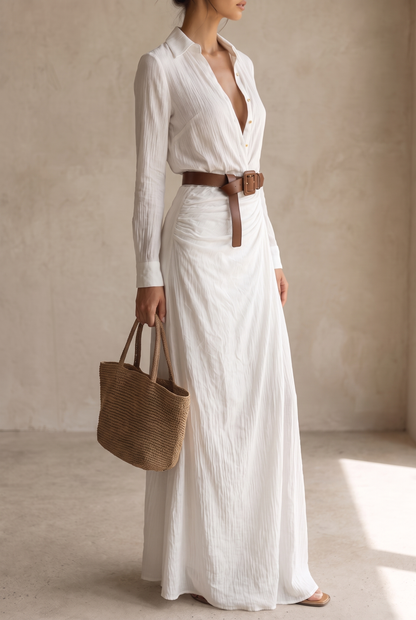 Second side view of the white maxi dress, belt end hanging loose, straw bag in hand and light textured fabric falling to the floor. 10