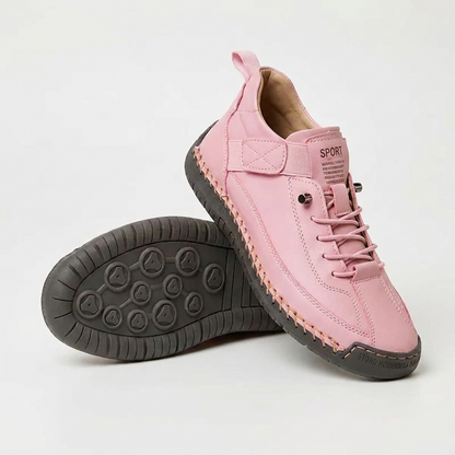 Pink trainers with dark grey sole and orange stitching, one upright, one turned to show the grip pattern 14