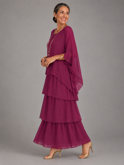 Side view of the tiered dress in deep magenta chiffon, worn by a smiling model with gold sandals. 22
