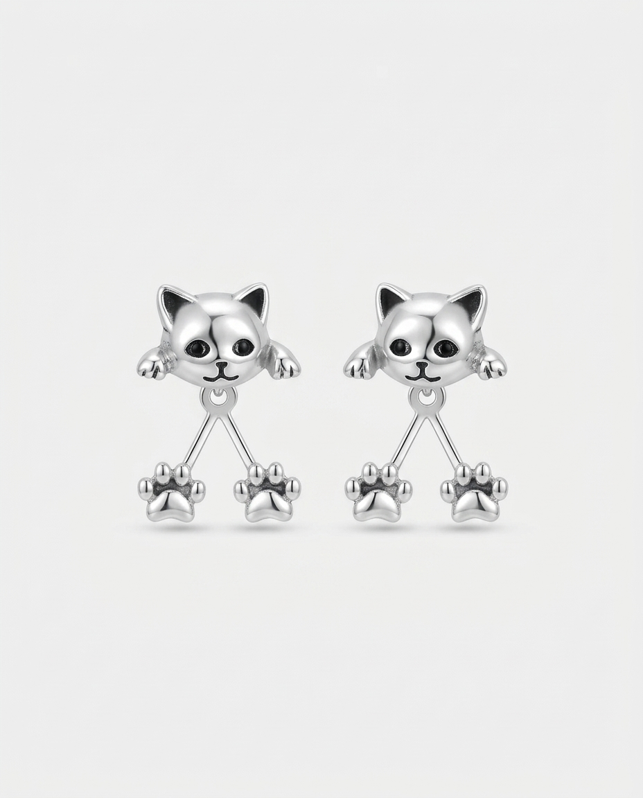 Pair of silver-tone cat head earrings with black eyes and two dangling paw prints each, on plain white 1