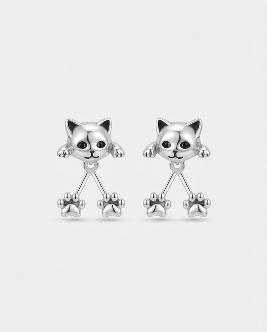 Pair of silver-tone cat head earrings with black eyes and two dangling paw prints each, on plain white 1