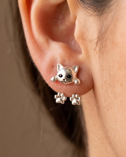 Close-up of the cat earring worn on a pierced lobe, showing the glossy face and paw details 3