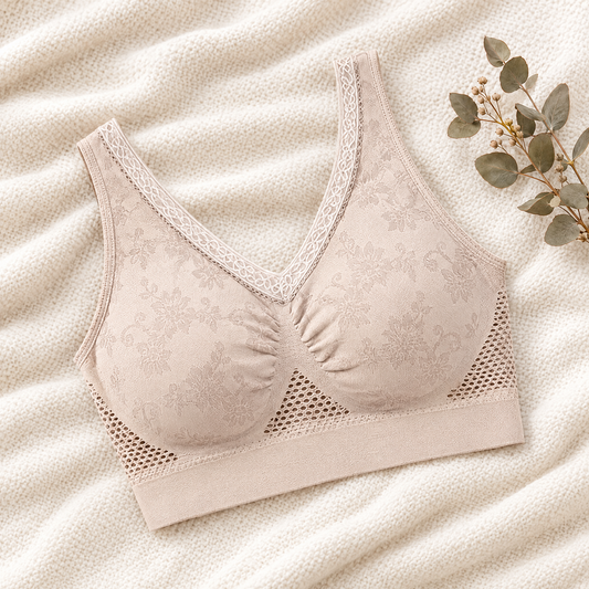 Beige floral jacquard bra with lace-trimmed V-neckline and mesh side panels, laid flat on cream knit with eucalyptus 1