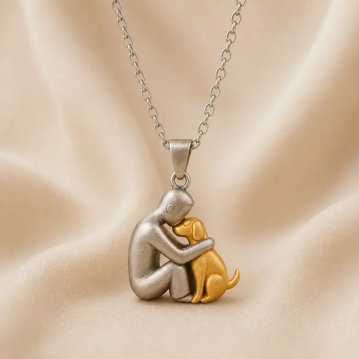 Side-on view of a matt silver-toned figure nuzzling a gold-toned dog, against ivory draped fabric 6