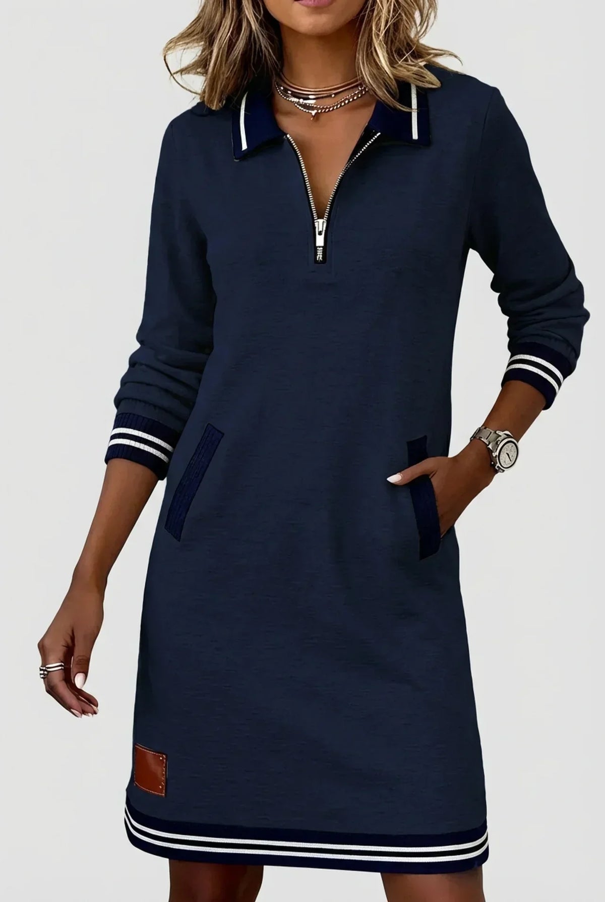 Close view of the navy dress on a model with hand in pocket, showing the zip collar and striped cuffs. 8