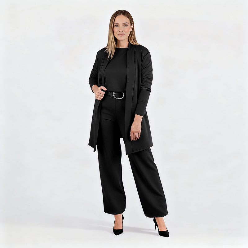 Full-length studio shot of a model in the black set with belt and black heels, one hand holding the open cardigan. 15