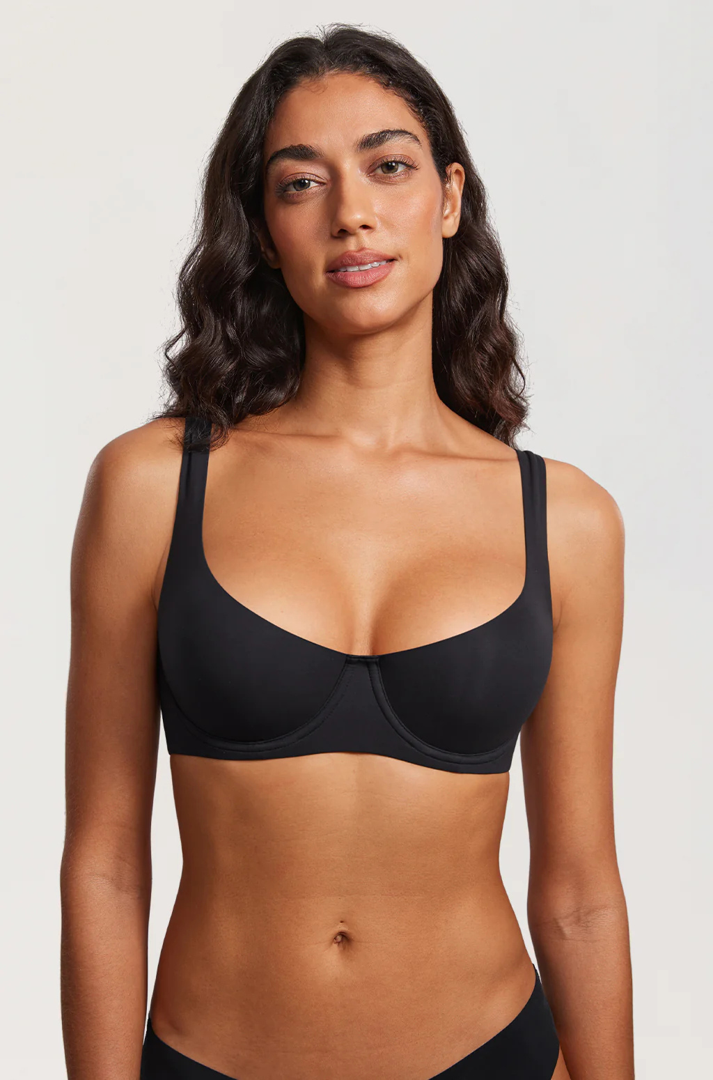 Front view of a model wearing the black balconette bra with wide shoulder straps and black briefs against a plain light background. 12