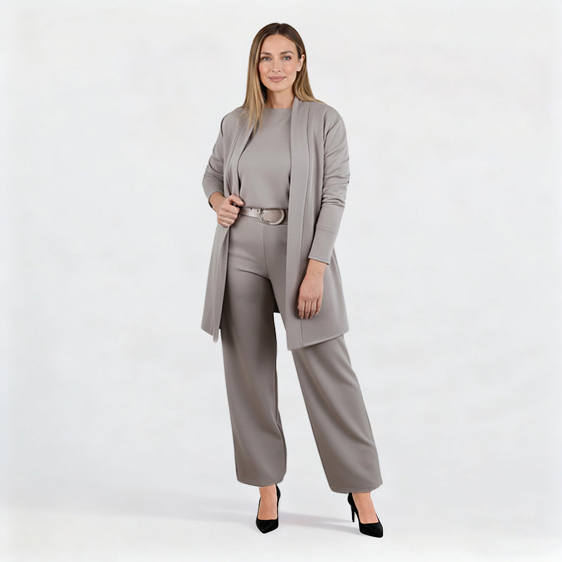 Full-length studio shot of a model in the grey set with belt and black heels, one hand holding the open cardigan. 11