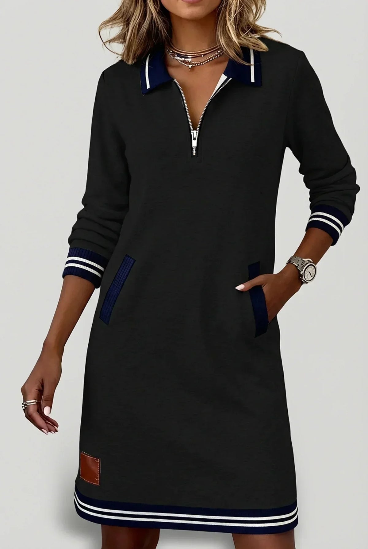Model in the black dress with hand in pocket, showing navy ribbed pocket trim, zip neckline and striped hem. 11