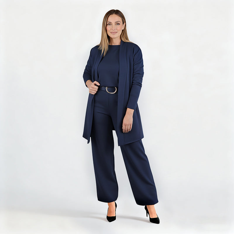 Full-length studio shot of a model in the navy set with belt and black heels, one hand holding the open cardigan. 12