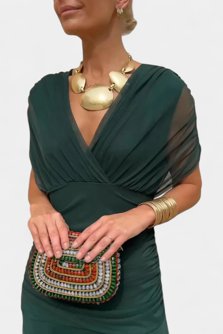 Close-up of the dark green V-neck bodice, showing the wrap-style pleating, sheer sleeve and fitted waistband. 7